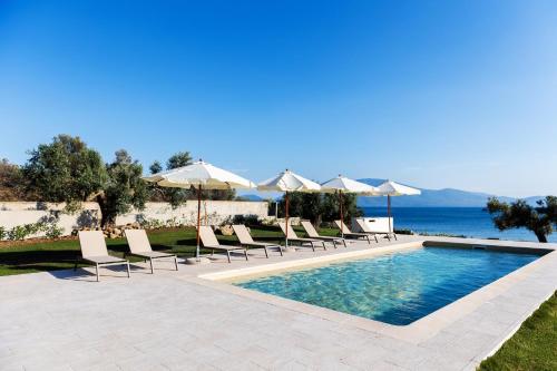 a pool with chairs and umbrellas next to the ocean at SeaSide Village in Politiká