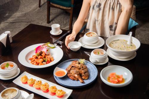 a woman is standing at a table with plates of food at DoubleTree by Hilton Shanwei in Shanwei