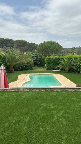 - une piscine dans une cour avec de l'herbe verte dans l'établissement Meublé 2P 40 m2 dans villa avec piscine à Vallauris, 4 km de la mer, à Vallauris