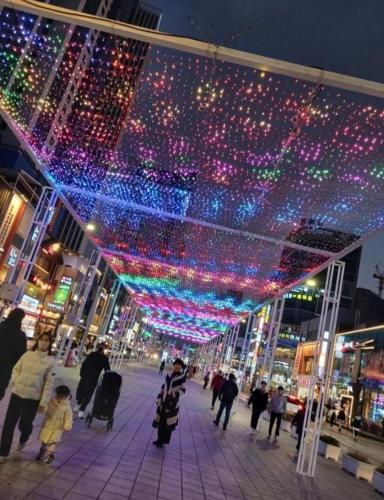 a group of people walking down a street with christmas lights at Elbon the stay with A1 in Busan