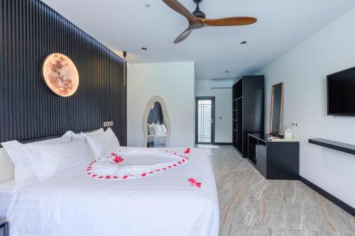 a bedroom with a white bed with flowers on it at Hakuna Maldives in Thoddoo