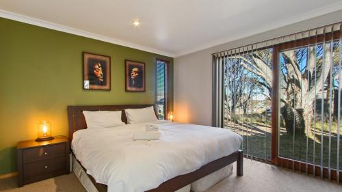 a bedroom with a large bed and a large window at Secret Hut in Dinner Plain