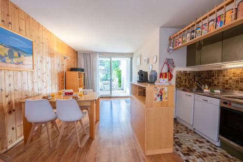 une cuisine avec une table et des chaises blanches dans l'établissement Petit Montagnard - Casier à ski - Parking, à Enchastrayes