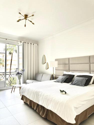 - une chambre blanche avec un grand lit et un canapé dans l'établissement Cannes Croisette - Studio Palais Miramar - Across the Beach - Next to Carlton Hotel, à Cannes