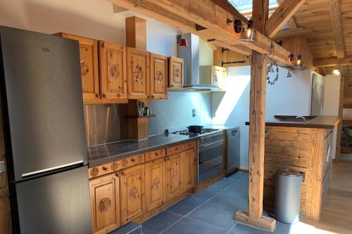 une cuisine avec des armoires en bois et un réfrigérateur en acier inoxydable dans l'établissement Le Beaulieu - Happy Rentals, à Chamonix-Mont-Blanc