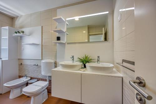 a bathroom with two sinks and a toilet and a mirror at Breeze Holiday Home - Sea View in Premantura