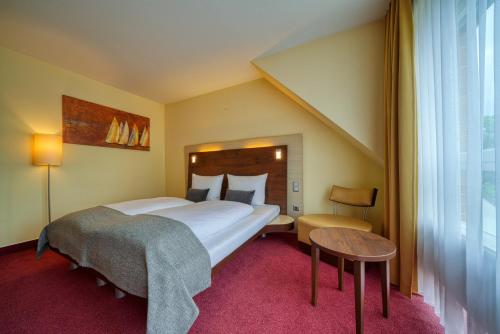 a hotel room with a large bed and a table at Hotel Wissers Fehmarn in Burg auf Fehmarn