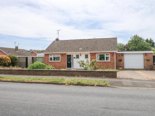 a red brick house with a white garage at Potter's Retreat in Dersingham