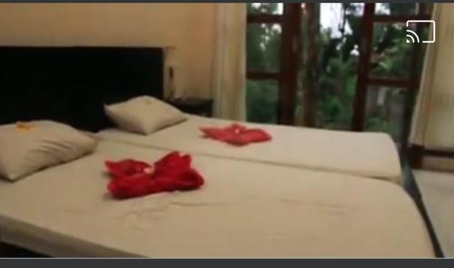 a white bed with two red flowers on it at Arnata Guest House & Pasraman Yoga Lokanata in Bangli