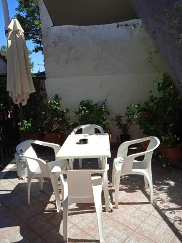 a white table and chairs and an umbrella on a patio at ΜΑΧΗ Ενοικιαζόμενα δωμάτια in Mithymna