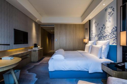 a hotel room with a bed and a television at Pullman Taiyuan in Taiyuan