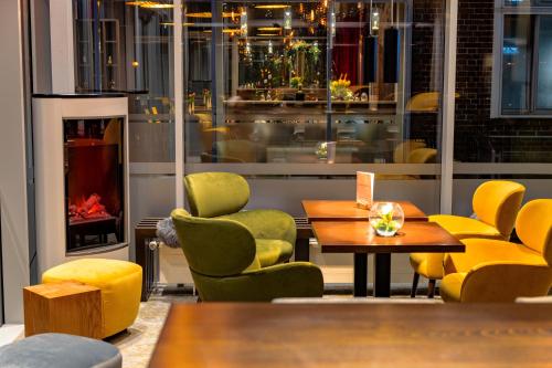 a restaurant with yellow chairs and tables and a fireplace at Hotel am Schlosspark in Güstrow