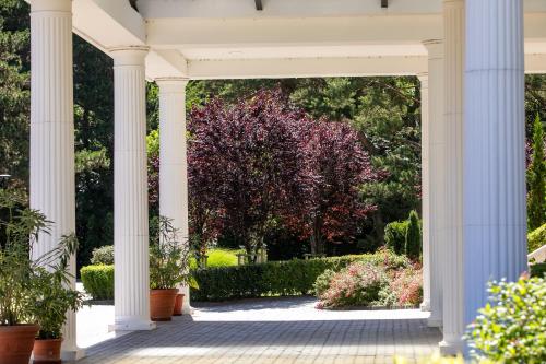 a white porch with plants and a tree at Hotel Golden Palace in Göd
