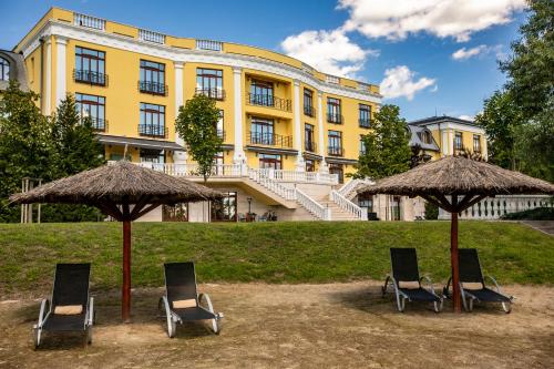 a group of chairs and umbrellas in front of a building at Hotel Golden Palace in Göd