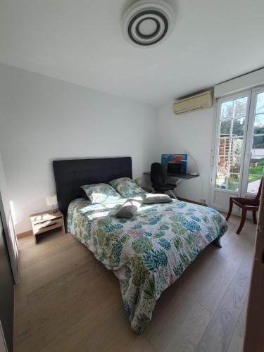 une chambre avec un lit avec une couette et une fenêtre dans l'établissement Maison de plain pied proche JO 2024, à Élancourt