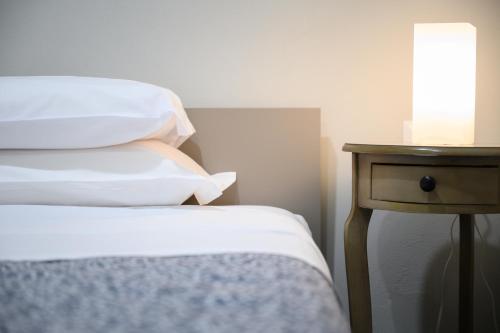 a bed with white sheets and a table with a lamp at GuestHouse o Affittacamere Magenta Baylon Suite in Rome