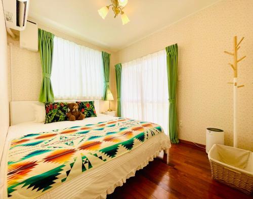 a bedroom with a bed with a teddy bear on it at Sunset Beach Vacation House in Chatan