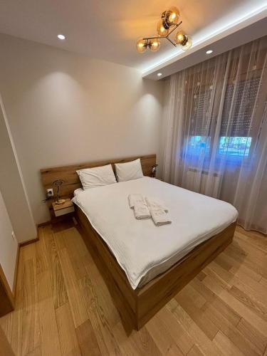 a bedroom with a bed with white sheets and a window at Apartmani Didić Kalman Zlatibor in Zlatibor