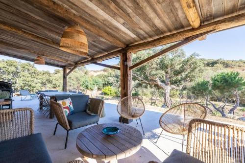 une terrasse couverte avec un toit en bois, une table et des chaises dans l'établissement maison à proximité plage de furnellu, à Sarragia