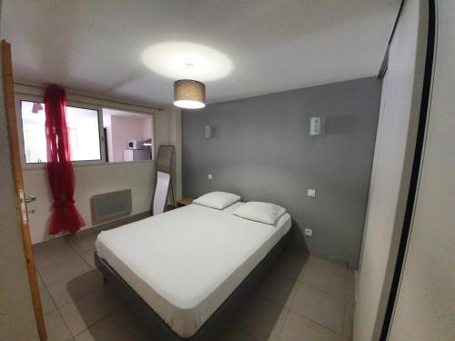 une chambre avec un lit blanc et une fenêtre dans l'établissement Joli appartement St Cyprien Village, à Saint-Cyprien