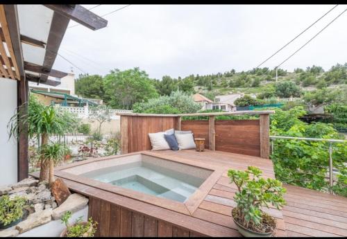 un bain à remous installé sur une terrasse en bois dans l'établissement Alt Niolon Maison, piscine vue mer et Marseille, à Le Rove