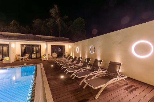 a row of chairs sitting next to a swimming pool at Hakuna Maldives in Thoddoo