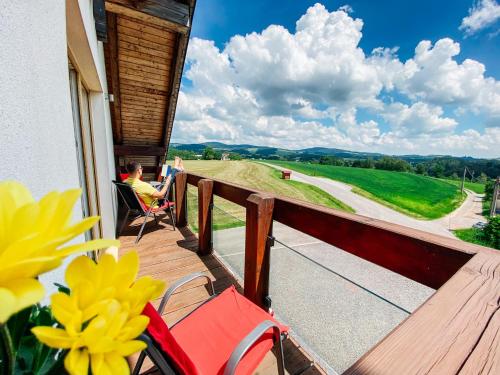 a woman sitting on a deck looking out at the countryside at Penzion Patriot in Výprachtice