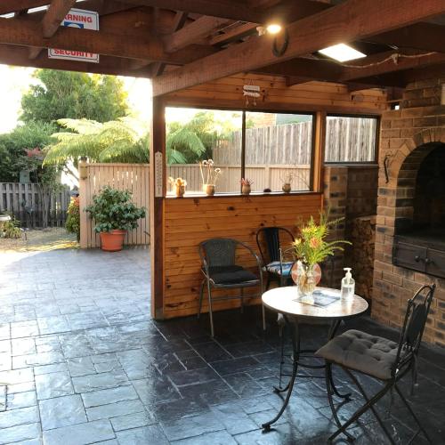 a patio with a table and chairs and a fireplace at Abs by the Bay in Taranna