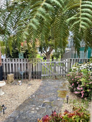 a garden with a fence and a tree and flowers at Abs by the Bay in Taranna