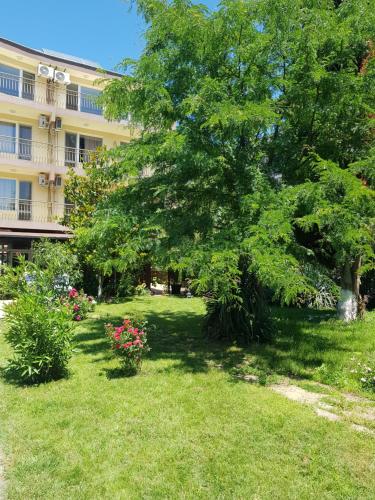 a yard with a tree and flowers in front of a building at Family Hotel Magnolia, Sunny Beach in Sunny Beach