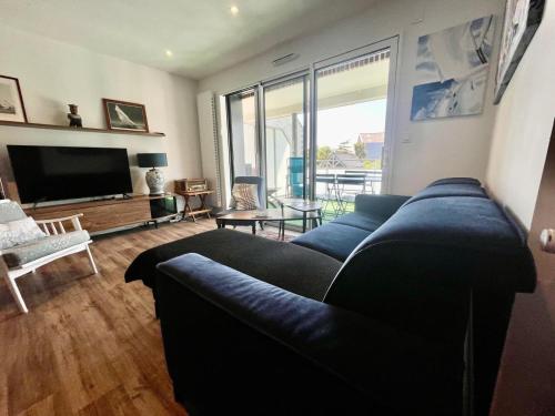 un salon avec un canapé et une télévision dans l'établissement jolie résidence proche du centre ville à Roscoff, à Roscoff
