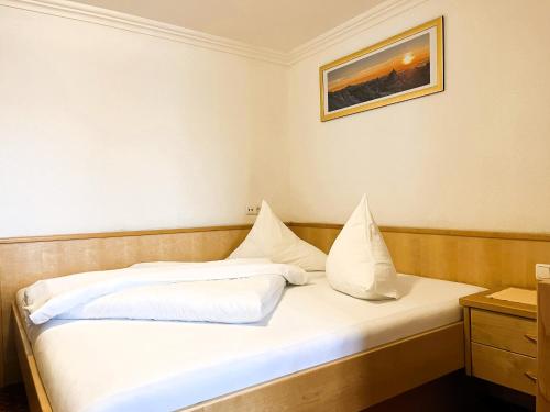 a bed with white sheets and pillows in a room at Hotel Garni Martina in Ischgl