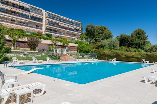une piscine avec des chaises et un bâtiment dans l'établissement Montfleuri, à Villeneuve-Loubet