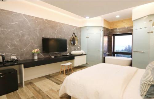 a bedroom with a bed and a desk with a television at Wangan 175 B&B in Shui-wa-chüeh