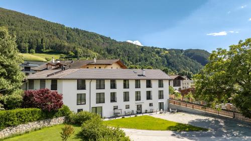a large white building with a mountain in the background at Untermoarhof Albeins in Bressanone