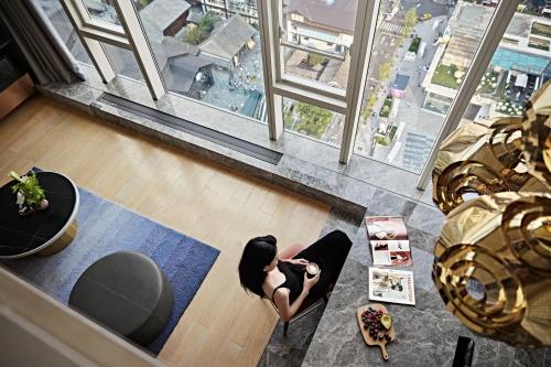 a woman standing in a living room looking out of a window at ISEYA Serviced Apart-ment Chengdu Taikoo Li Flagship in Chengdu