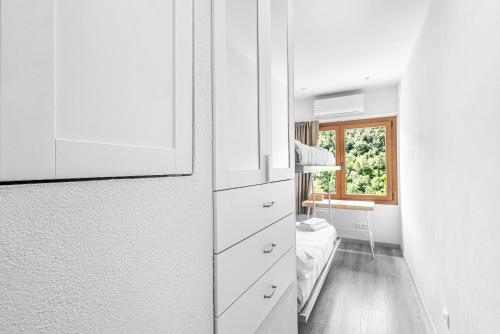 a white bedroom with a bed and a window at Cal Ton in San Quírico Safaja