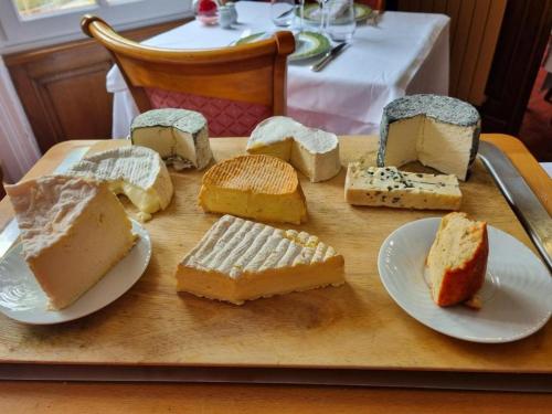 a tray with different types of cheeses on a table at La Villa Bois Joli HOTEL RESTAURANT in Bagnoles de l'Orne