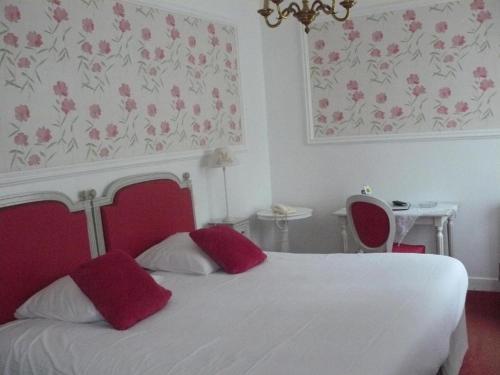 a bedroom with a white bed with red pillows at La Villa Bois Joli HOTEL RESTAURANT in Bagnoles de l'Orne