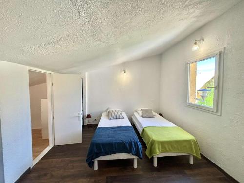 deux lits dans une chambre avec une fenêtre dans l'établissement Appartement 105 résidence Terra Bella 1 Porticcio, à Porticcio