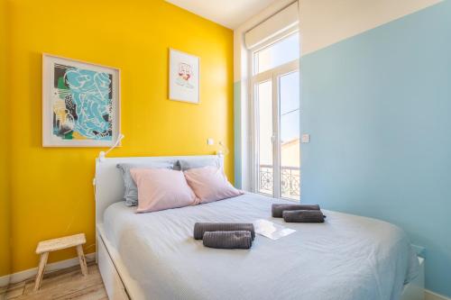 a bedroom with a bed with a yellow wall at T2 avec balcon à Malmousque - Calme & vue mer in Marseille