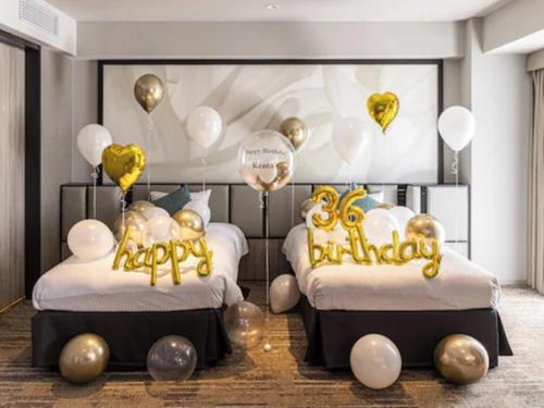 two beds with gold and white balloons in a room at ORIENTAL HOTEL UNIVERSAL CITY in Osaka