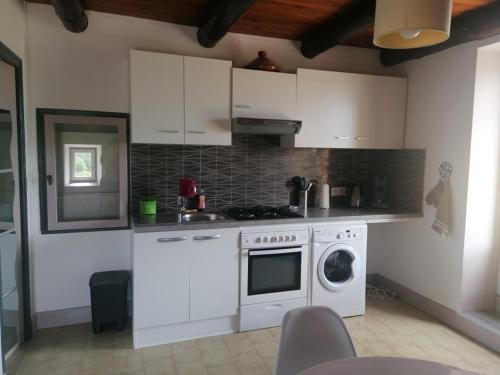 une cuisine avec des armoires blanches et une machine à laver dans l'établissement Studio maison en pierre avec terrasse, à Rosières