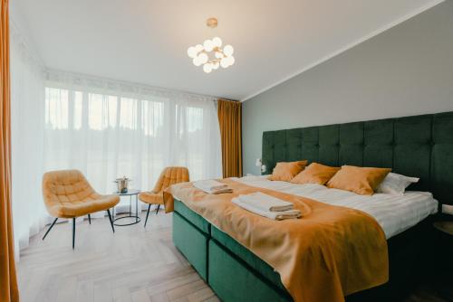 a bedroom with a large bed with an orange blanket at Vanagu muiža in Aizupes