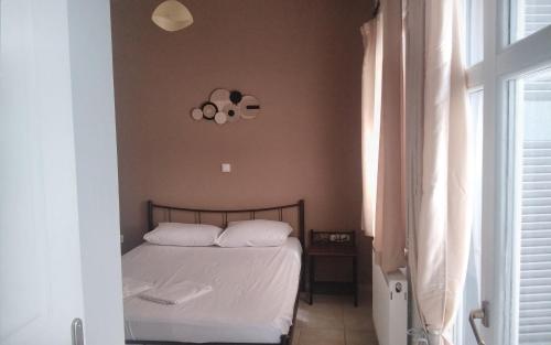 a bedroom with a bed with white sheets and a window at Ανδρος Αρκουδα in Andros