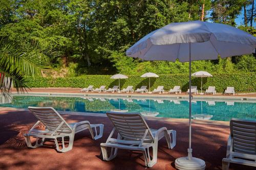 deux chaises et un parasol à côté d'une piscine dans l'établissement Ile de France, mobil-home cosy au coeur d' une forêt avec piscine, à Saint-Chéron