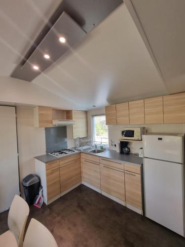 une cuisine avec des armoires en bois et un réfrigérateur blanc dans l'établissement Ile de France, mobil-home cosy au coeur d' une forêt avec piscine, à Saint-Chéron
