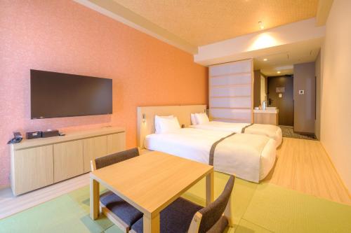 a hotel room with a bed and a table and a tv at Tosei Hotel Cocone Tsukiji Ginza Premier in Tokyo