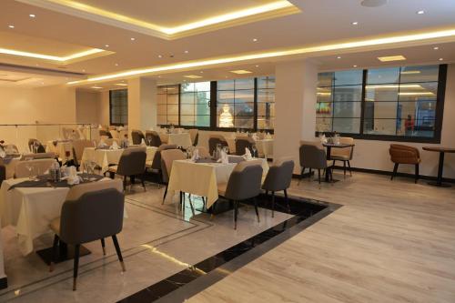 a restaurant with white tables and chairs and windows at Bentark Hotel in Addis Ababa