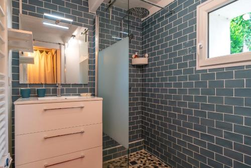 a bathroom with blue tiled walls and a sink at L'air du large - Maison à 15min à pied de la plage in Le Palais